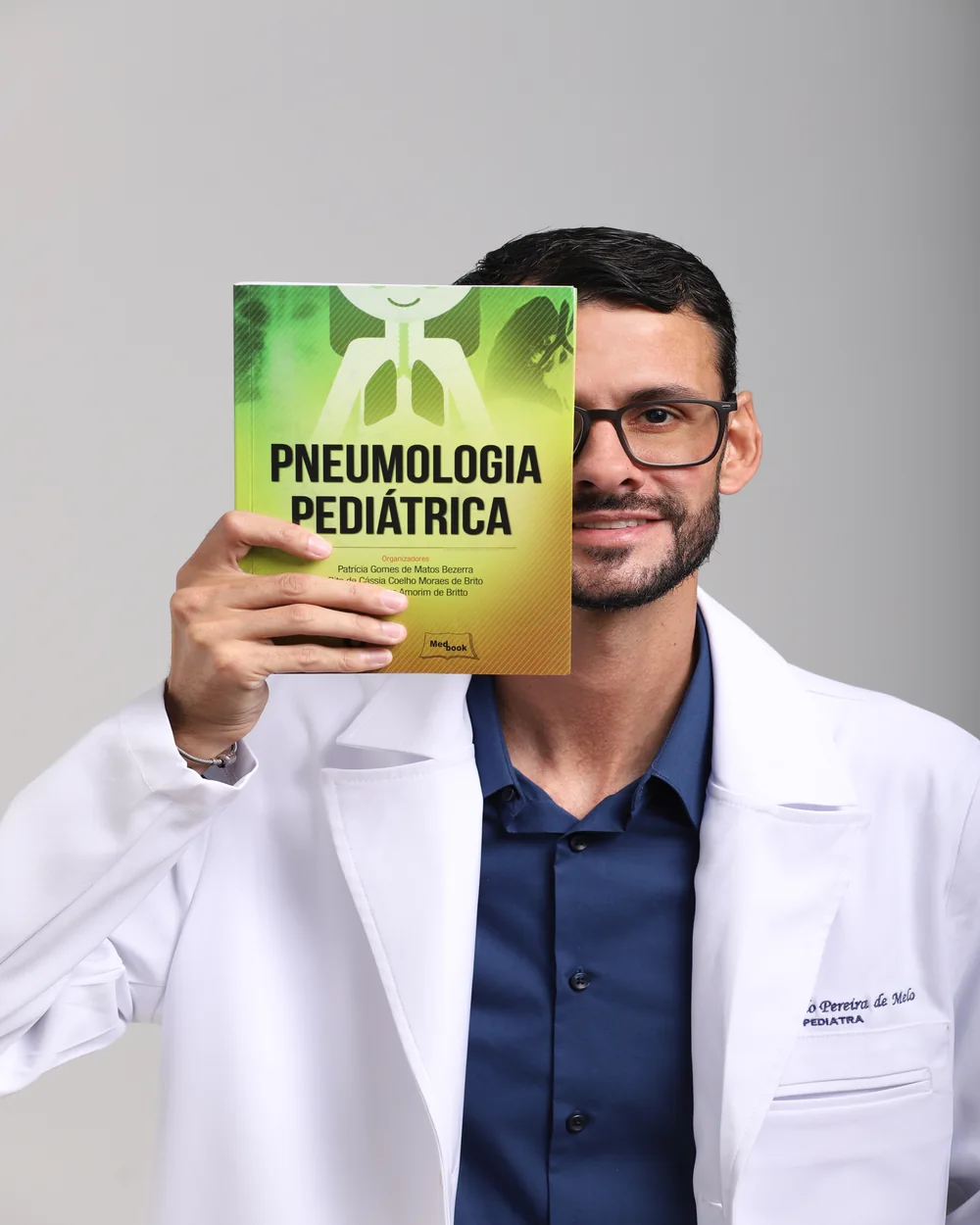 Dr. Ricardo Melo segurando um livro de pneumologia pediátrica
